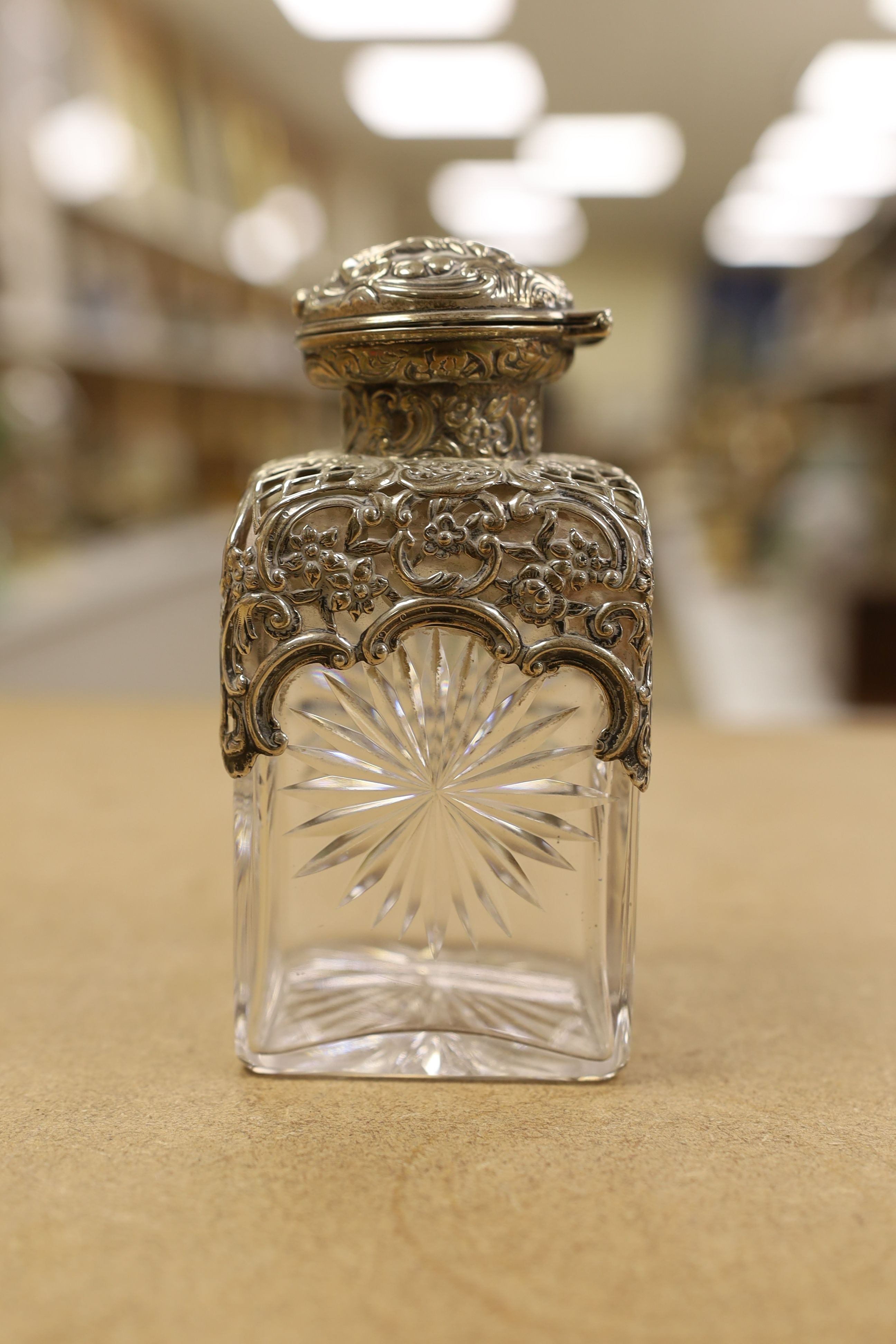 A pair of late Victorian repousse silver mounted cut glass scent bottles with stoppers, William Comyns, London, 1898, height 14.3cm.